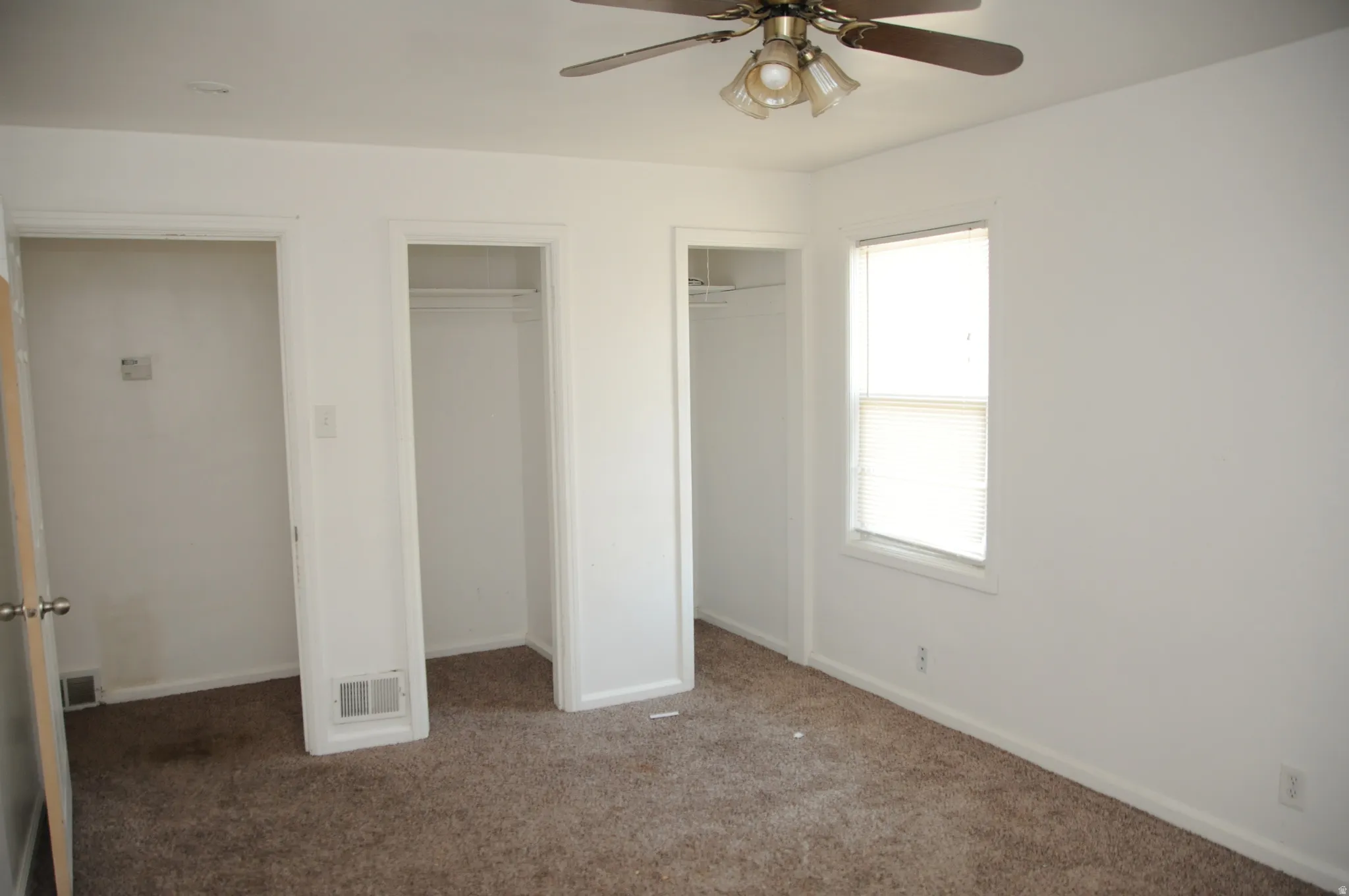 Unfurnished bedroom featuring two closets, carpet floors, and ceiling fan