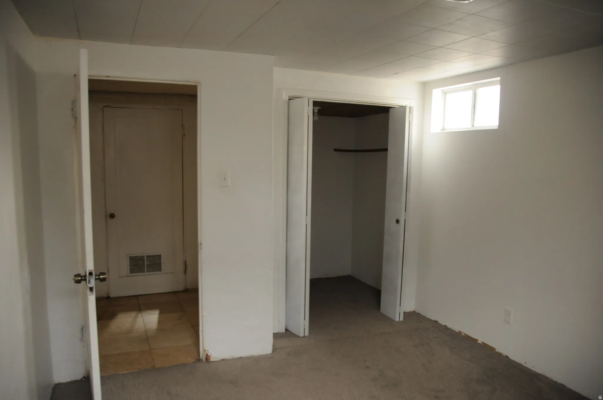Unfurnished bedroom featuring light carpet, a spacious closet, and light tile patterned floors