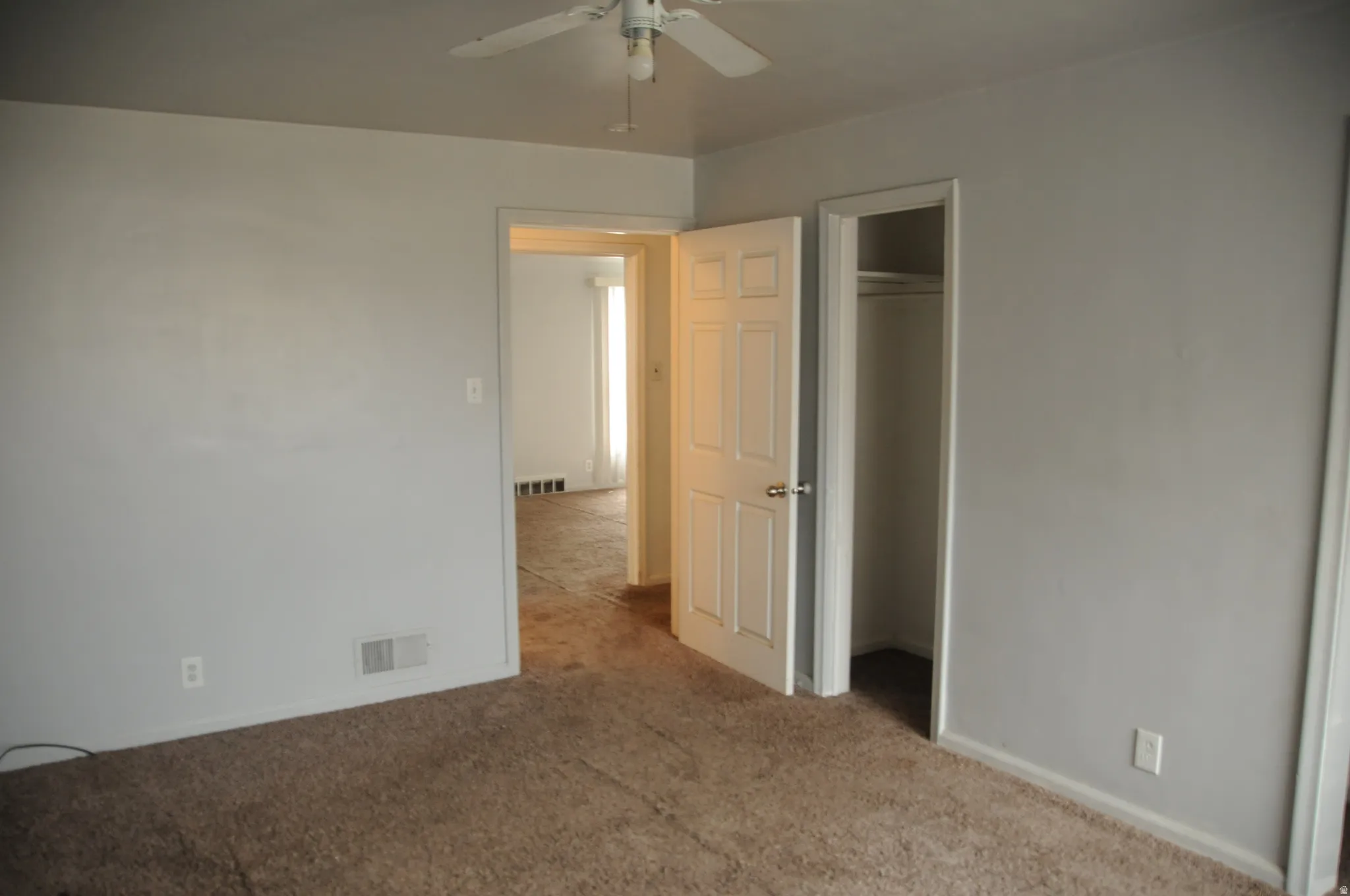 Unfurnished bedroom featuring light colored carpet, ceiling fan, and a spacious closet