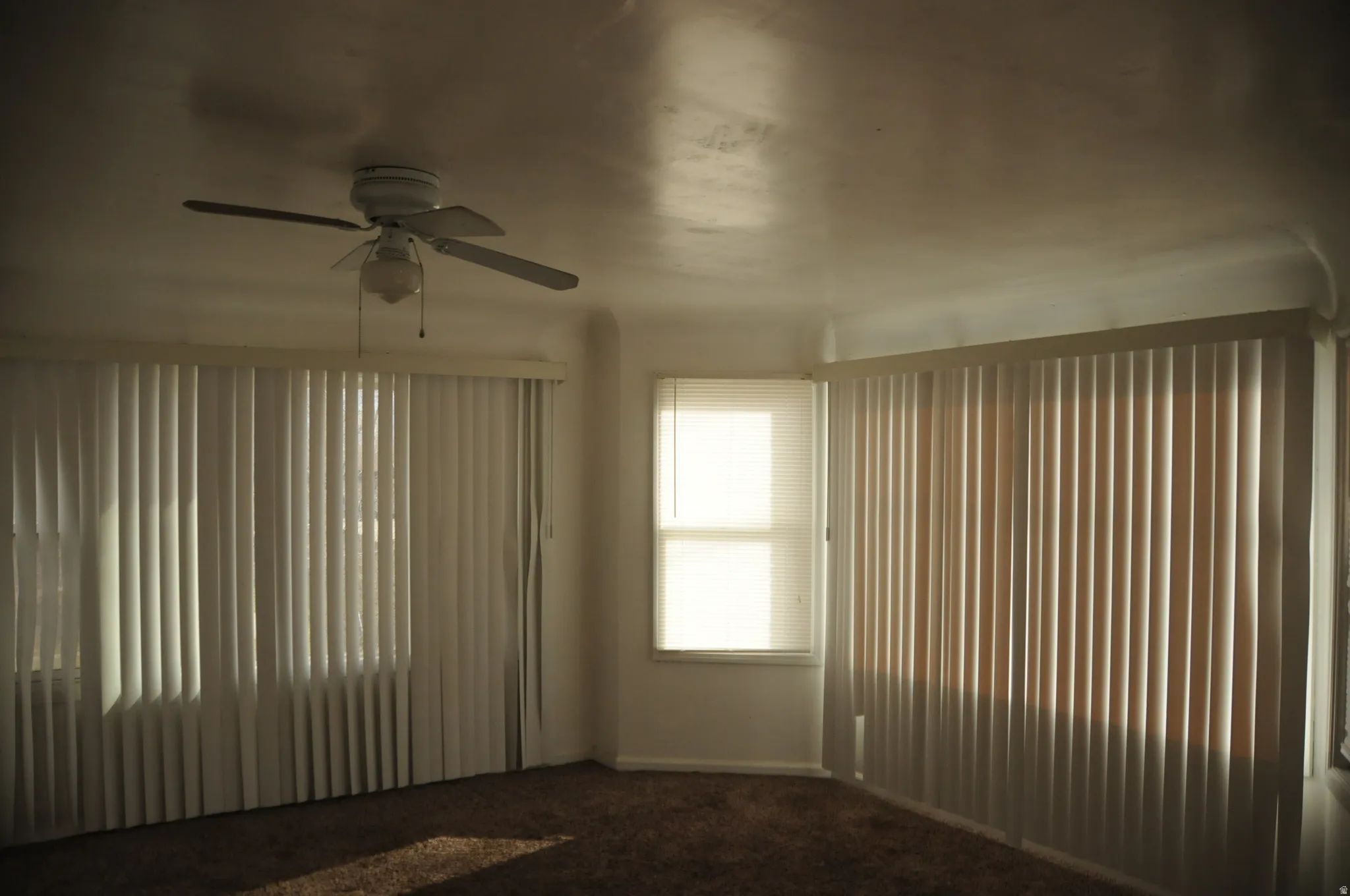 Spare room featuring dark carpet and a ceiling fan