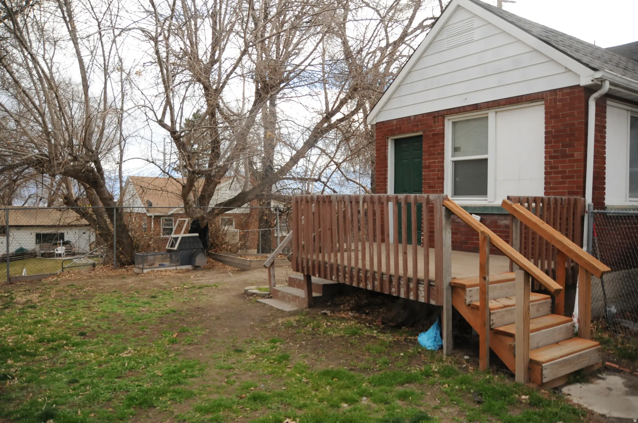 Rear view of house featuring brick siding, a wooden deck, and roof with shingles