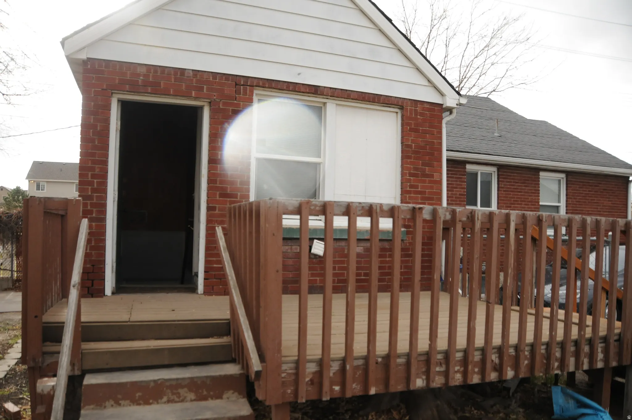 Rear view of house featuring brick siding and a wooden deck