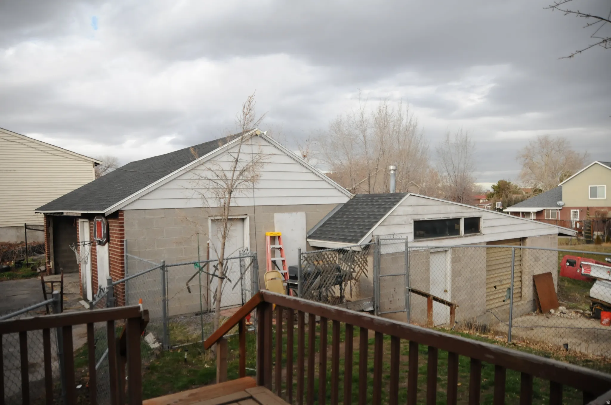 Rear view of property featuring a fenced backyard, roof with shingles, a deck, and an outdoor structure