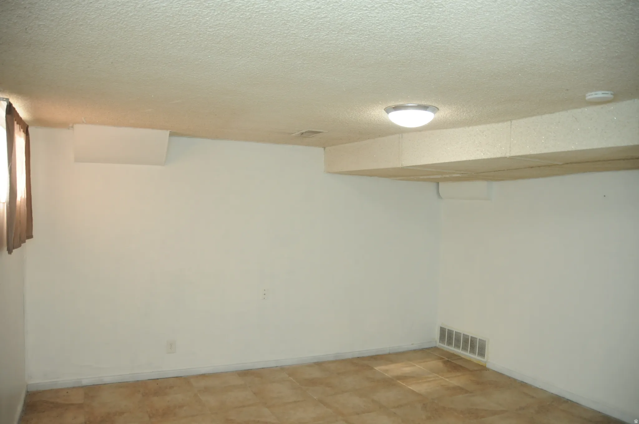 Finished basement featuring a textured ceiling and baseboards