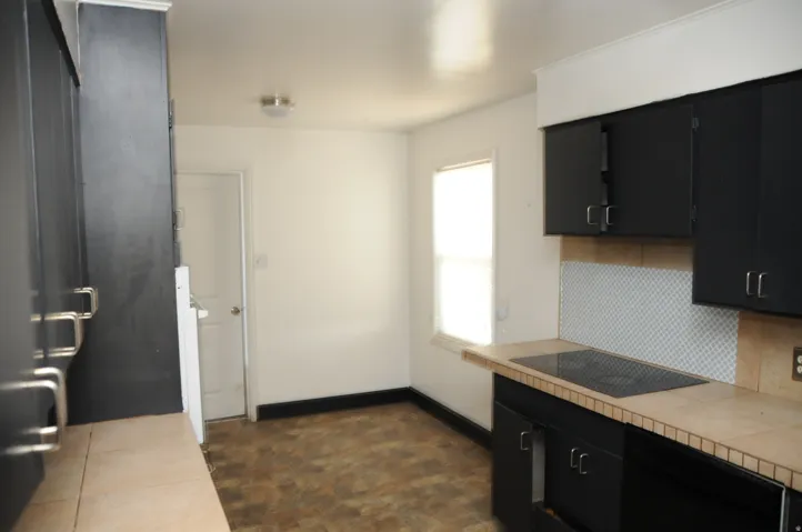 Kitchen featuring dark cabinets, tile counters, black appliances, and tasteful backsplash