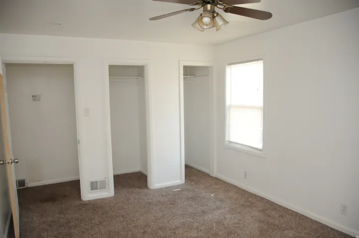 Unfurnished bedroom featuring two closets, carpet floors, and ceiling fan