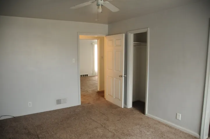 Unfurnished bedroom featuring light colored carpet, ceiling fan, and a spacious closet