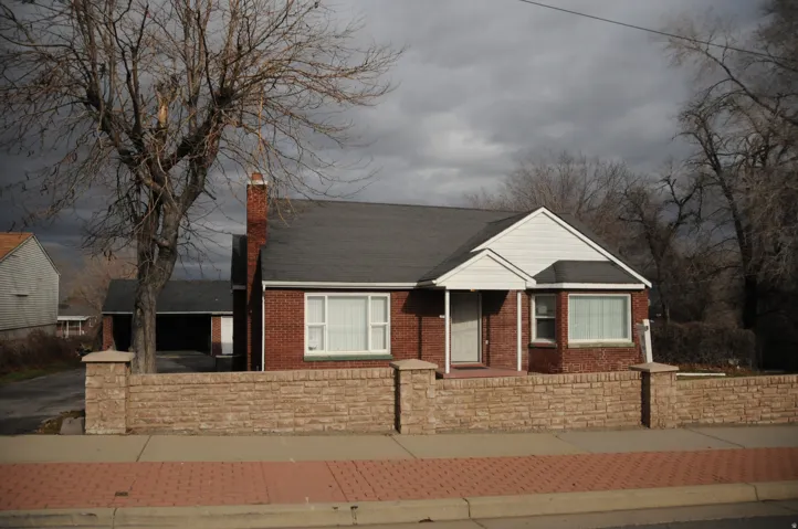 View of front of house with a chimney, brick siding, a fenced front yard, driveway, and covered porch
