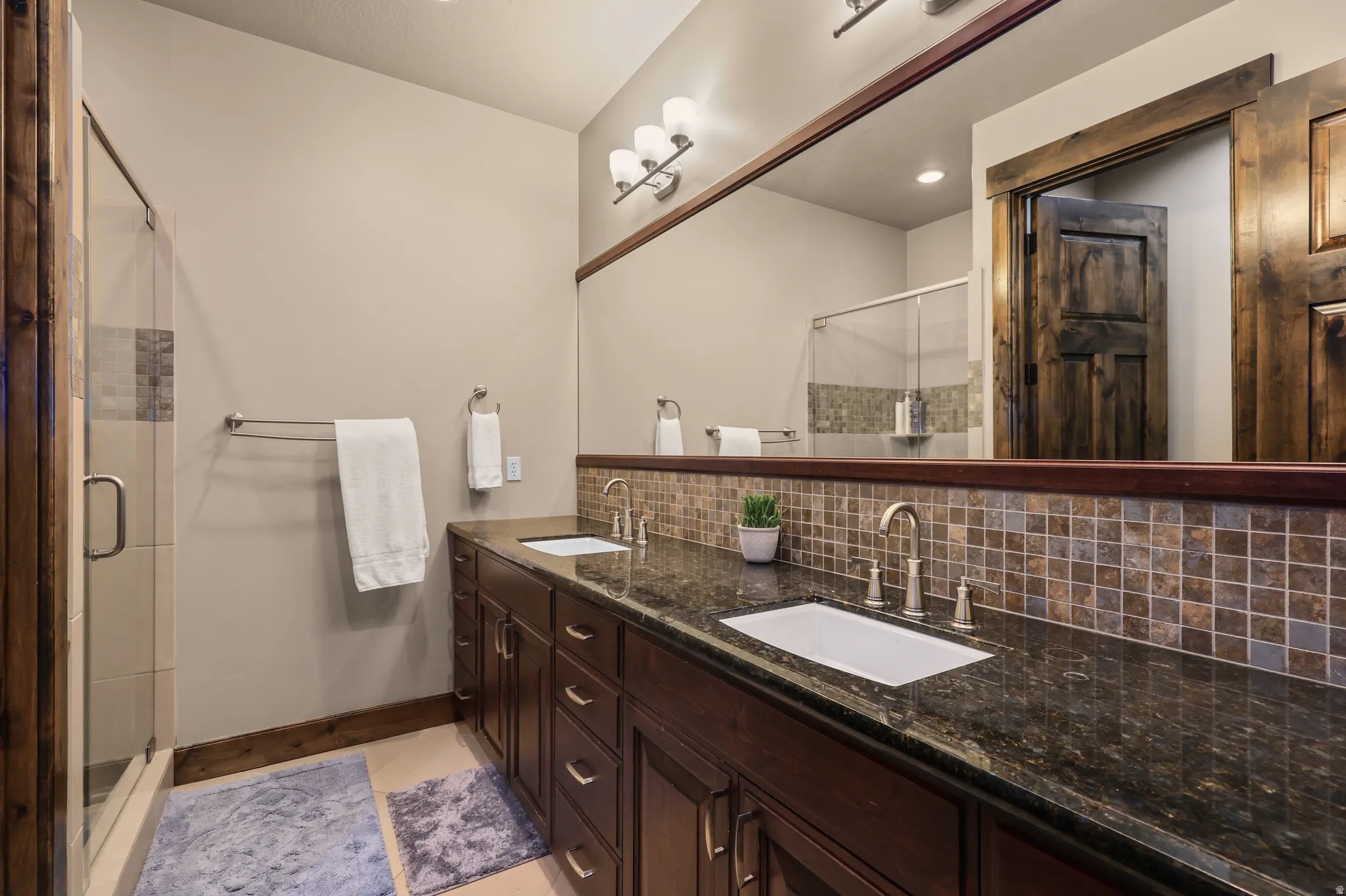 Full bathroom with backsplash, double vanity, and a stall shower