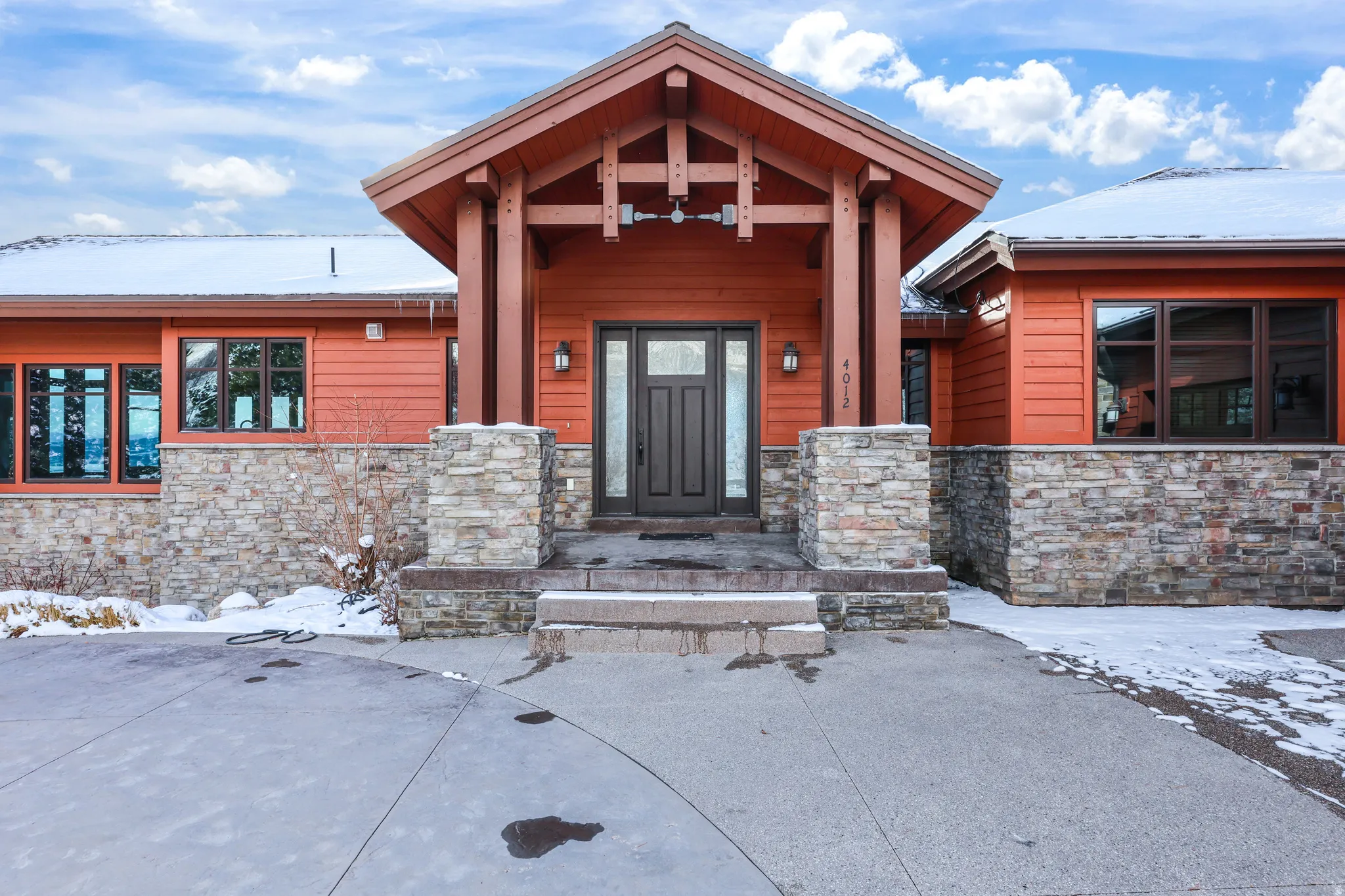 Snow covered property entrance featuring stone siding