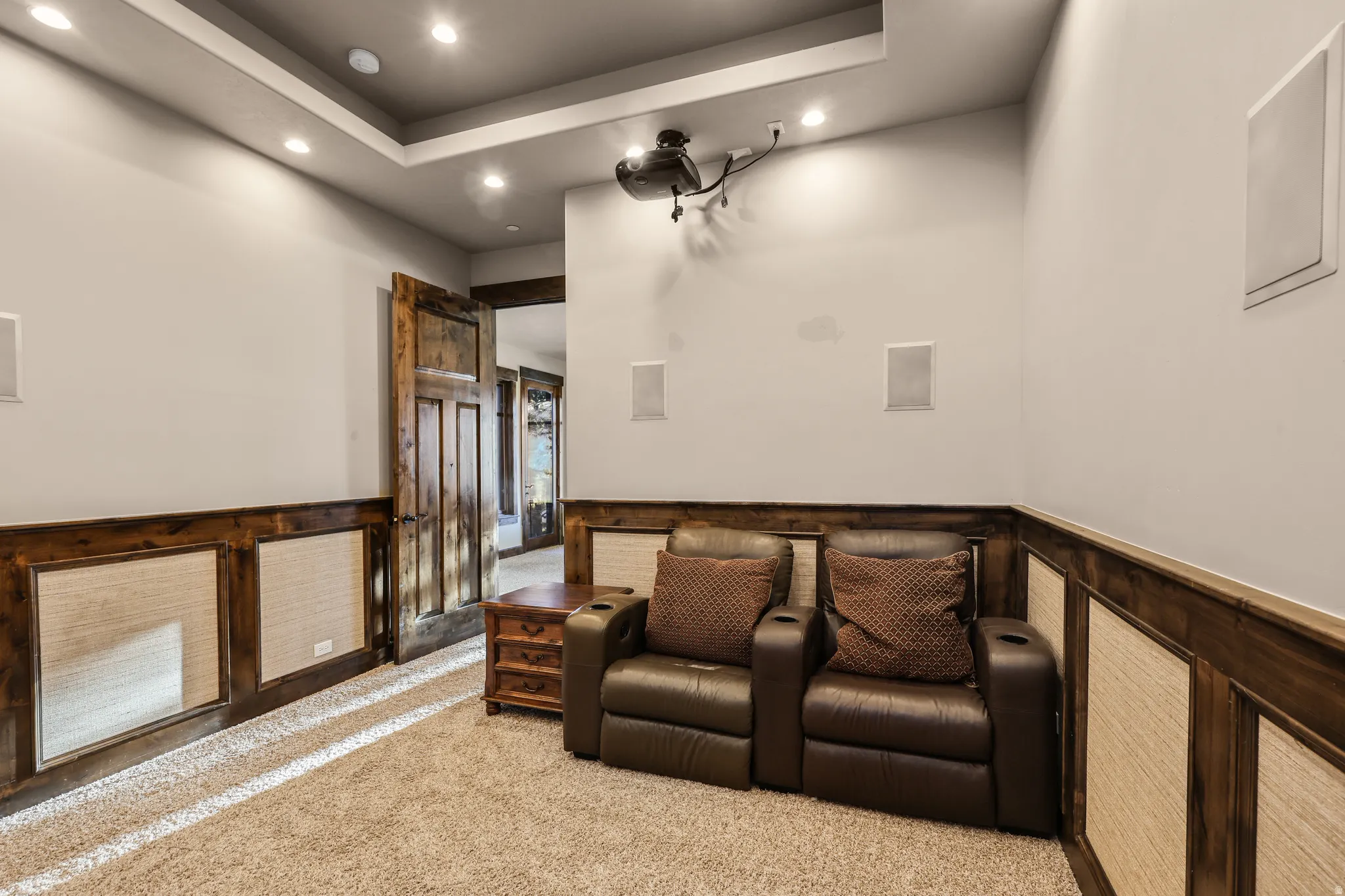 Cinema featuring a wainscoted wall, recessed lighting, a tray ceiling, carpet, and a decorative wall