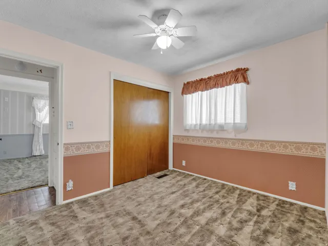 Unfurnished bedroom featuring carpet flooring, a closet, a textured ceiling, and ceiling fan