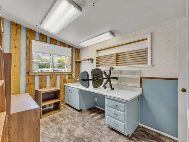 Office featuring wallpapered walls, carpet, lofted ceiling, and wainscoting