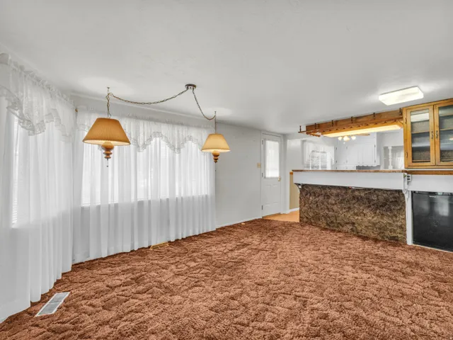 Kitchen with glass insert cabinets, light carpet, brown cabinetry, and decorative light fixtures