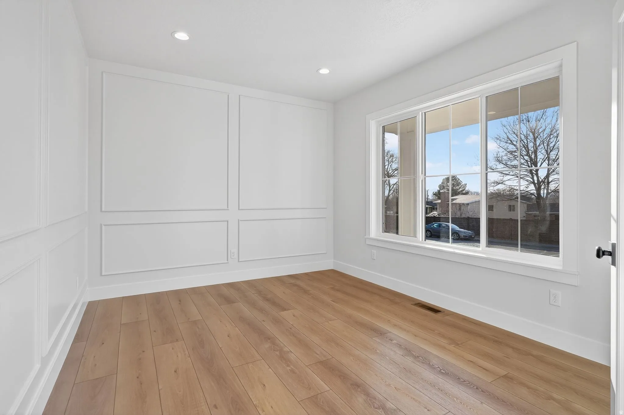 Studio or office room with a decorative wall, light wood-type flooring, and recessed lighting, picture window