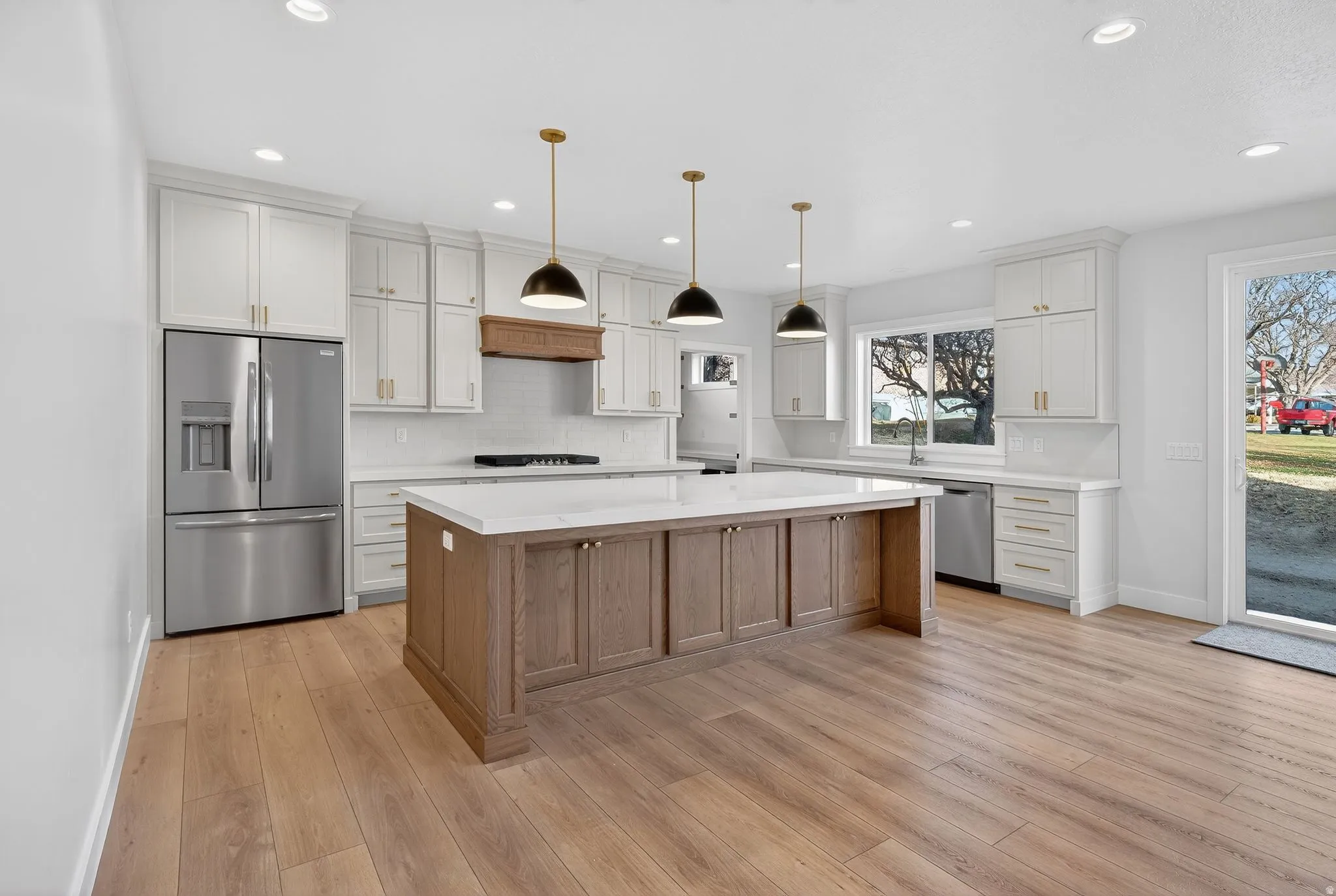 Kitchen featuring appliances with stainless steel finishes, a center island, brown cabinets, pendant lighting, and white cabinetry