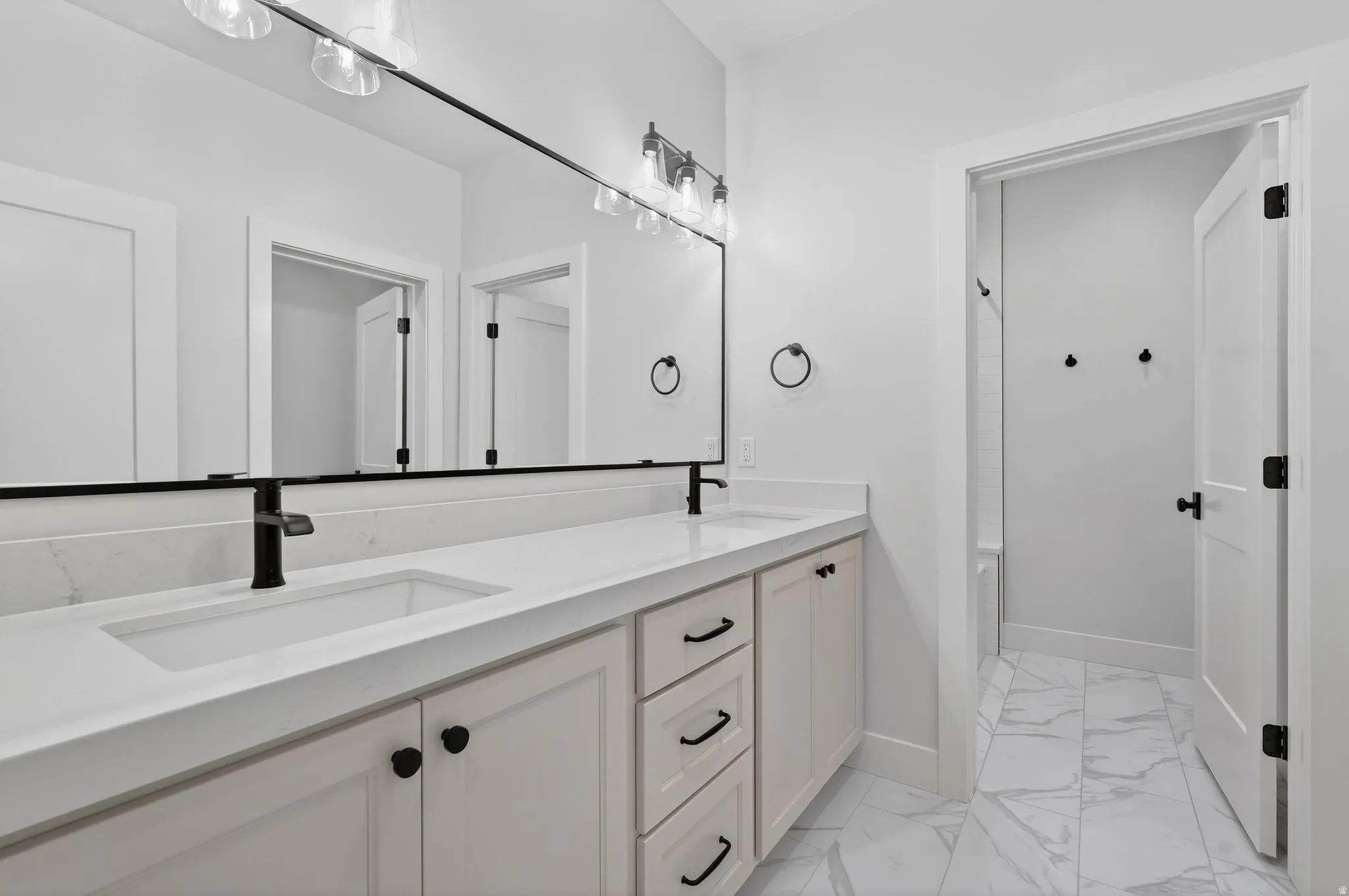Full bath featuring light marble finish floors, double vanity, and shower / bathtub combination