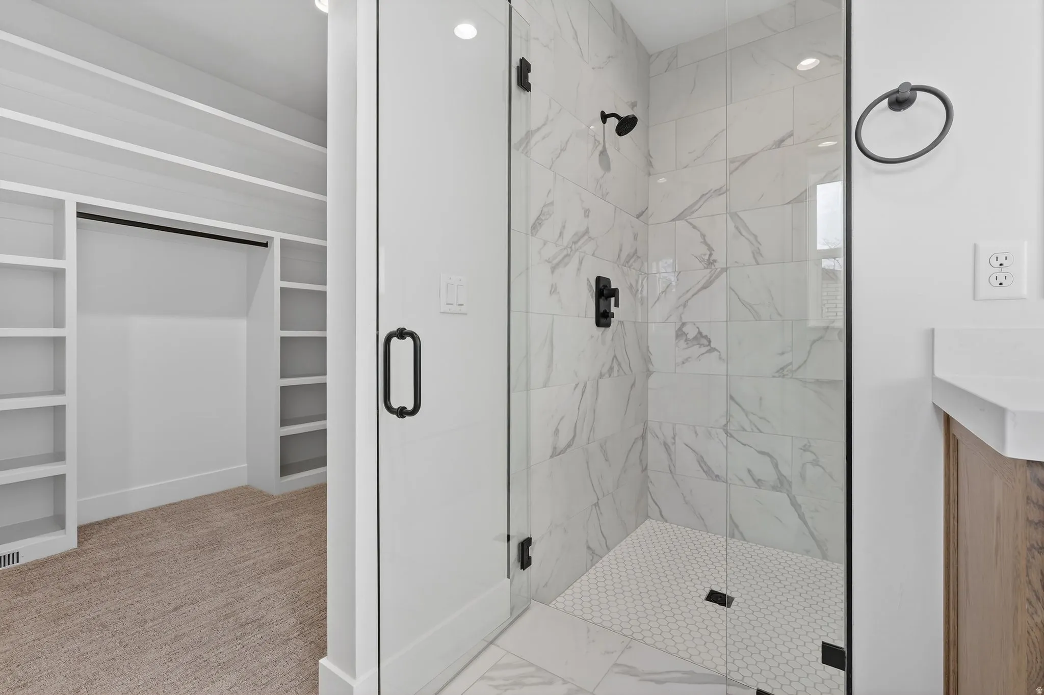 Bathroom with a huge walk in closet, a marble finish  2 headed shower, vanity, and light marble finish floors
