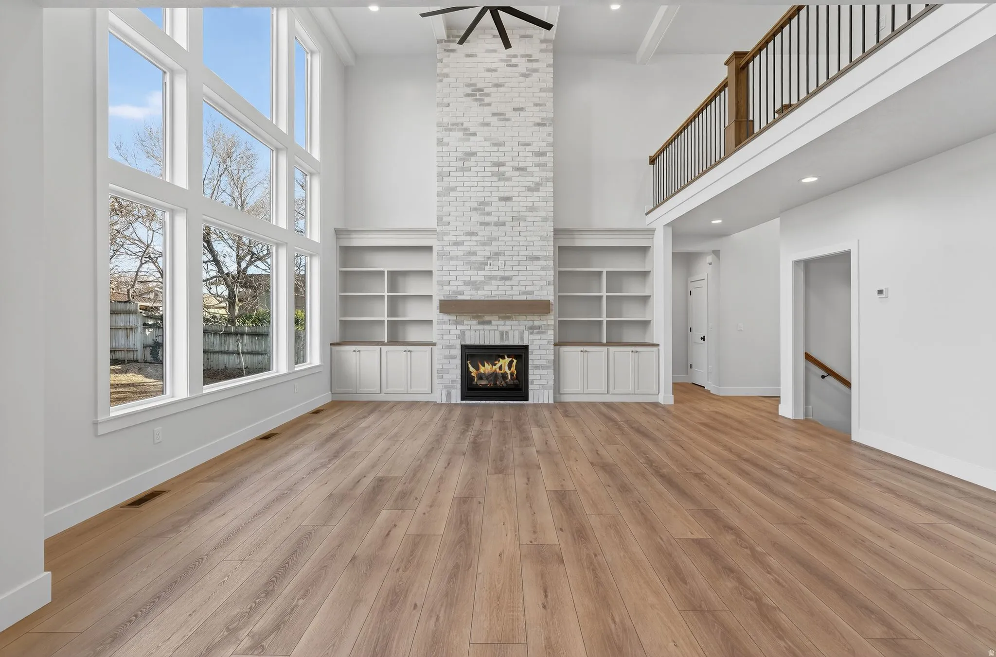 Family room featuring a high ceiling, a large fireplace, light wood-type flooring, built in features, and recessed lighting