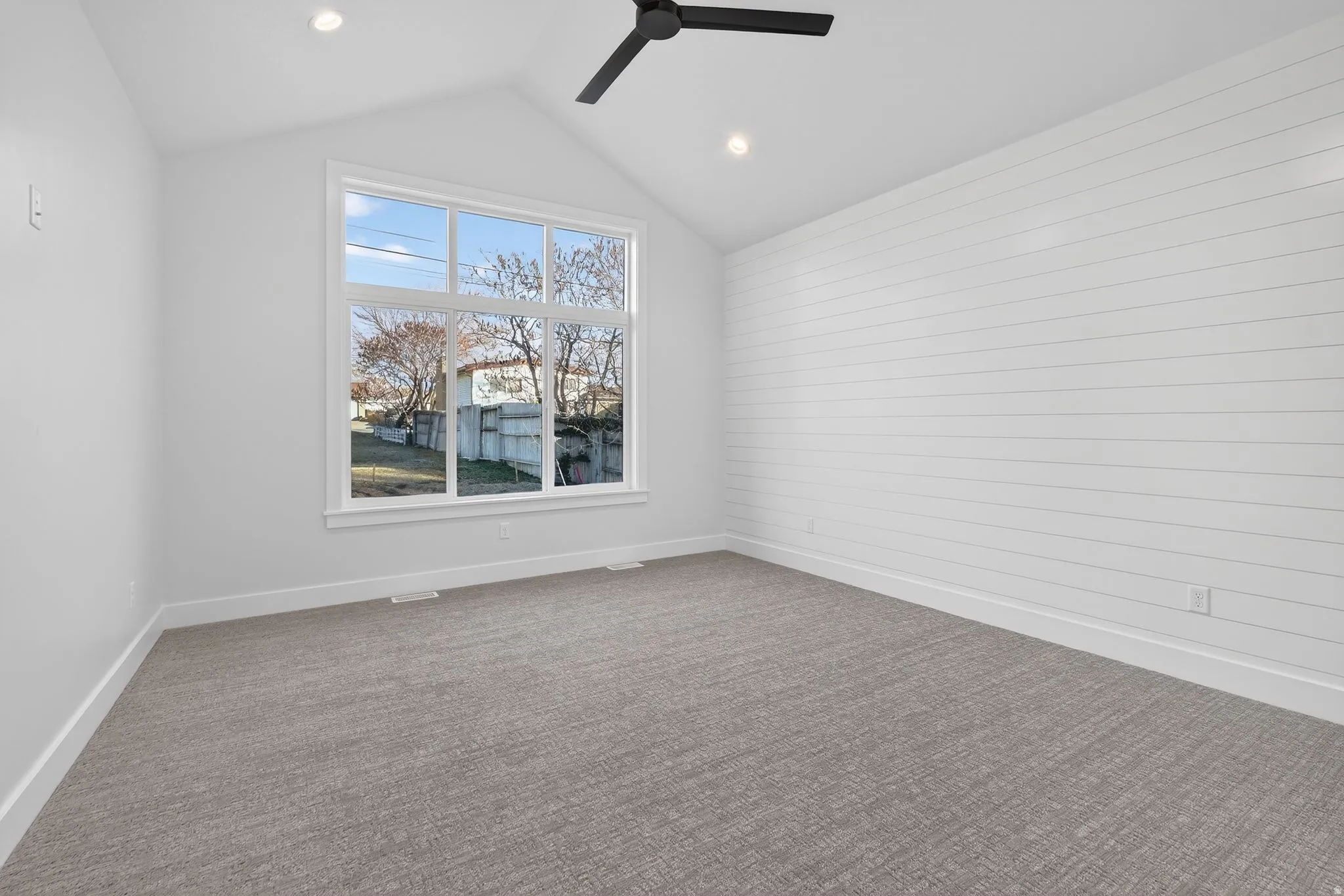 Vaulted ceiling Master on-suite with light carpet, a ceiling fan, and wooden Shiplap designed walls Main floor on-suite