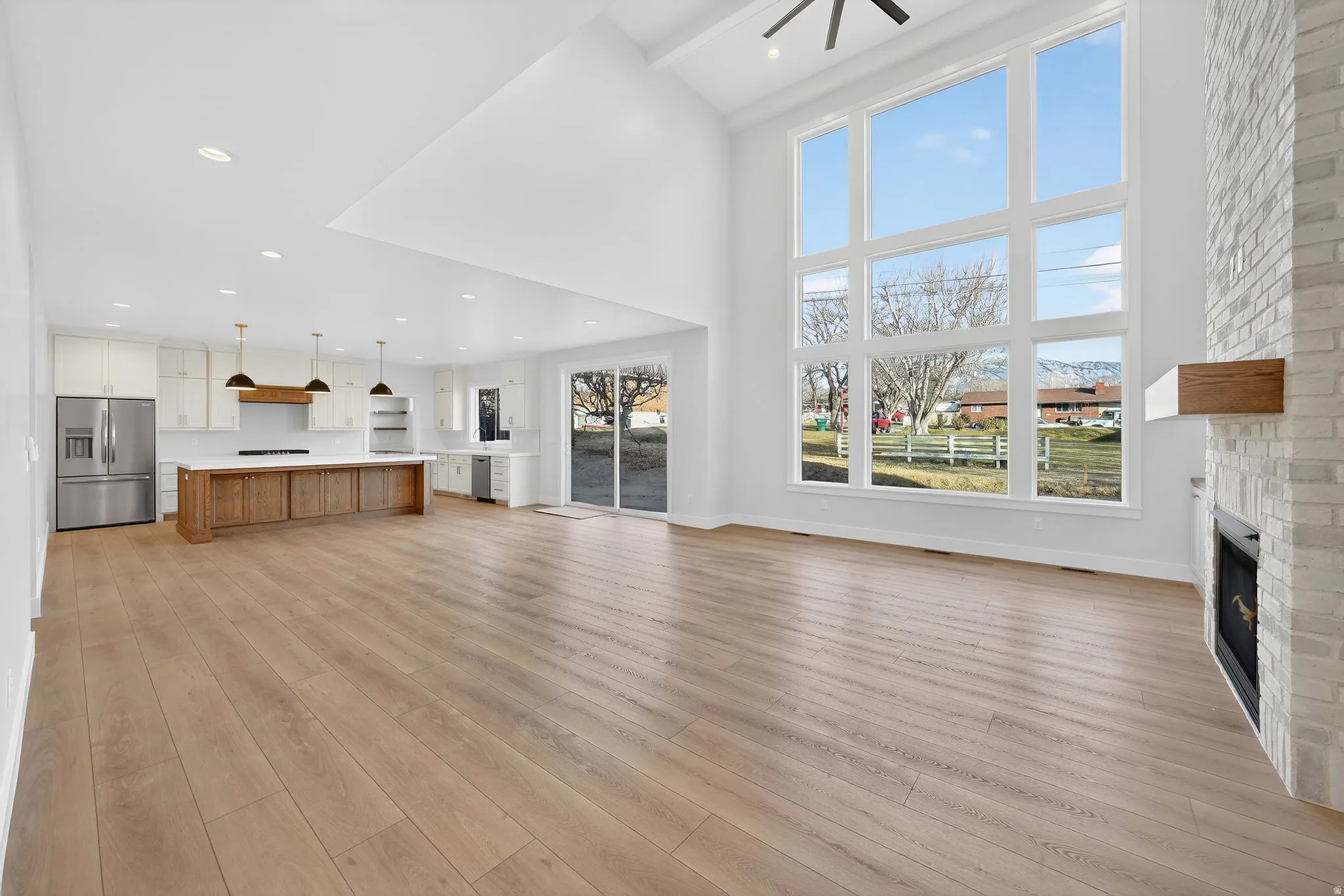 Unfurnished living room with a fireplace, light wood-style floors, a high ceiling, and a ceiling fan