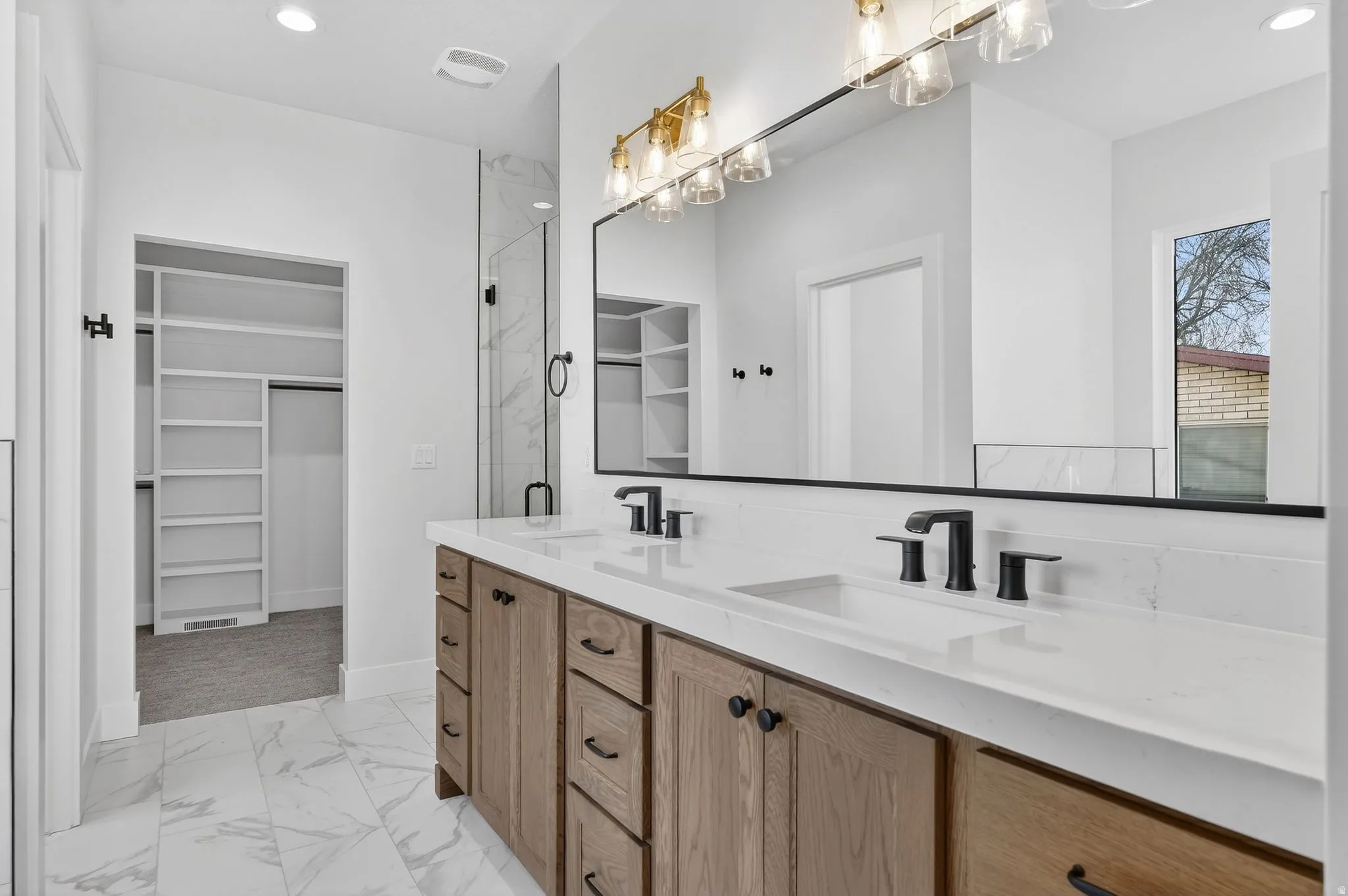 Primary Bathroom with a spacious closet, light marble finish floors, double vanity, recessed lighting, and a marble finish