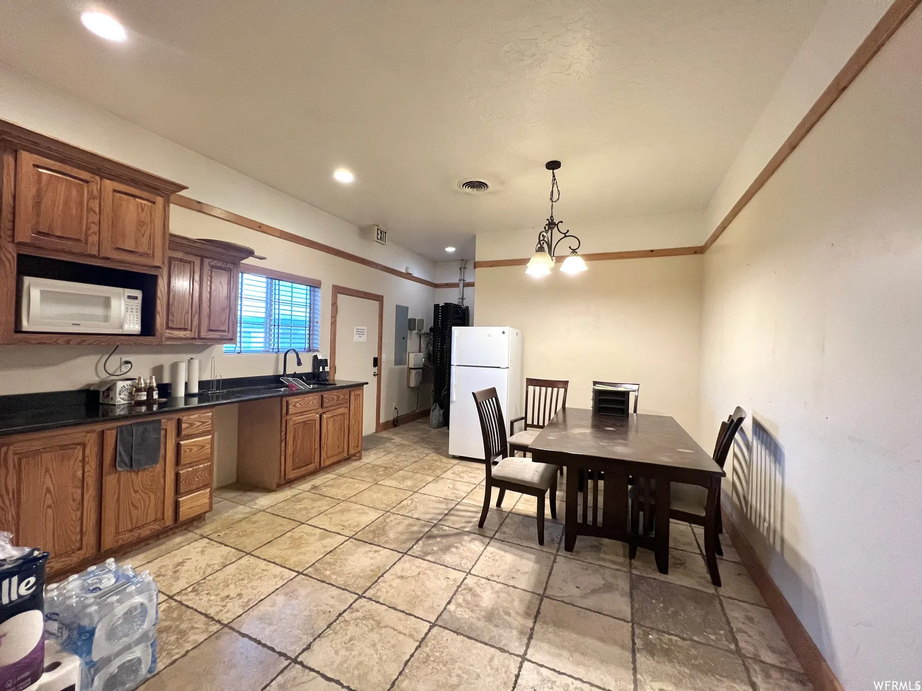 Kitchen featuring white appliances, pendant lighting, recessed lighting, brown cabinets, and a chandelier
