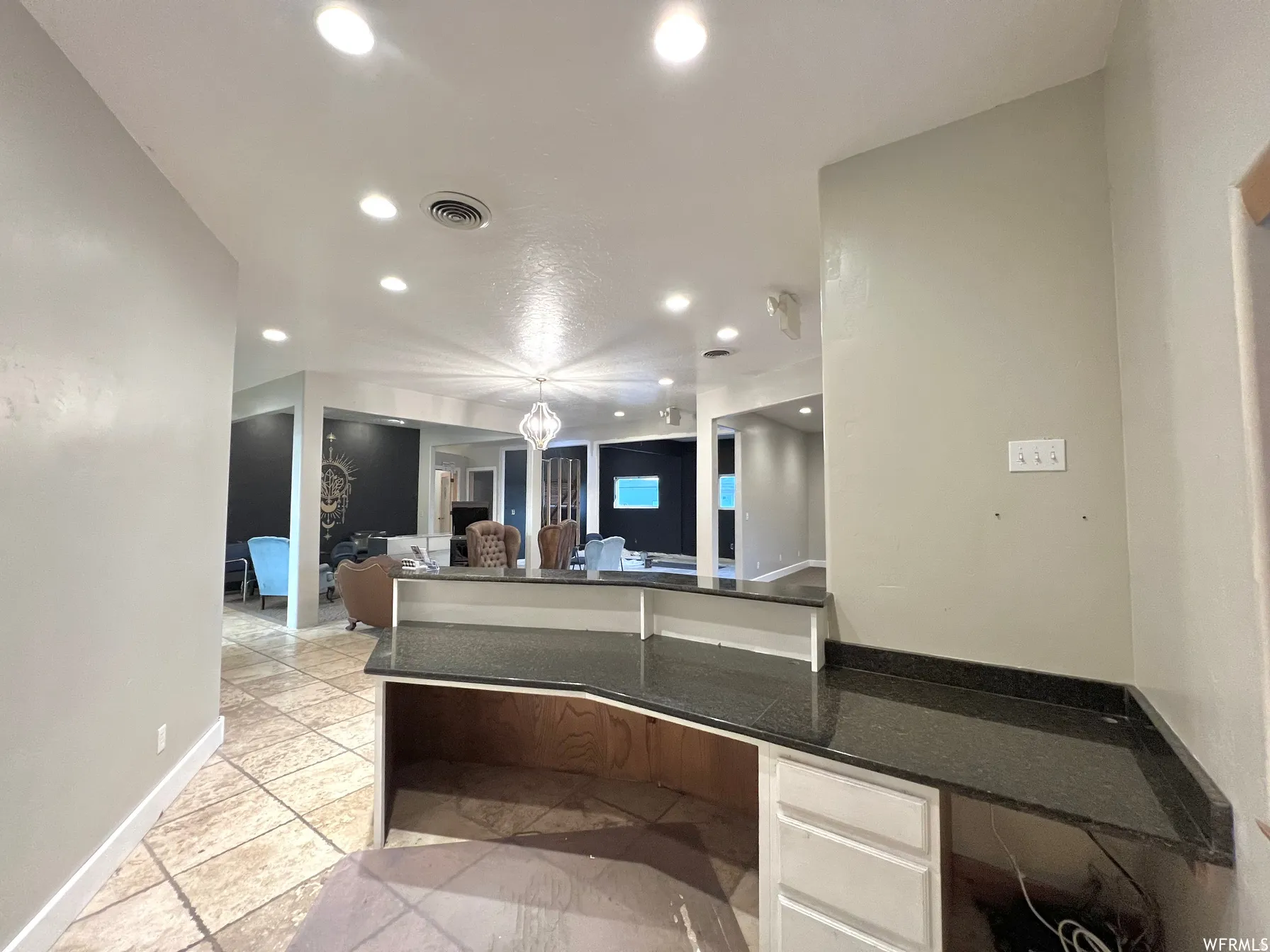 Kitchen with dark stone counters, recessed lighting, a peninsula, and pendant lighting