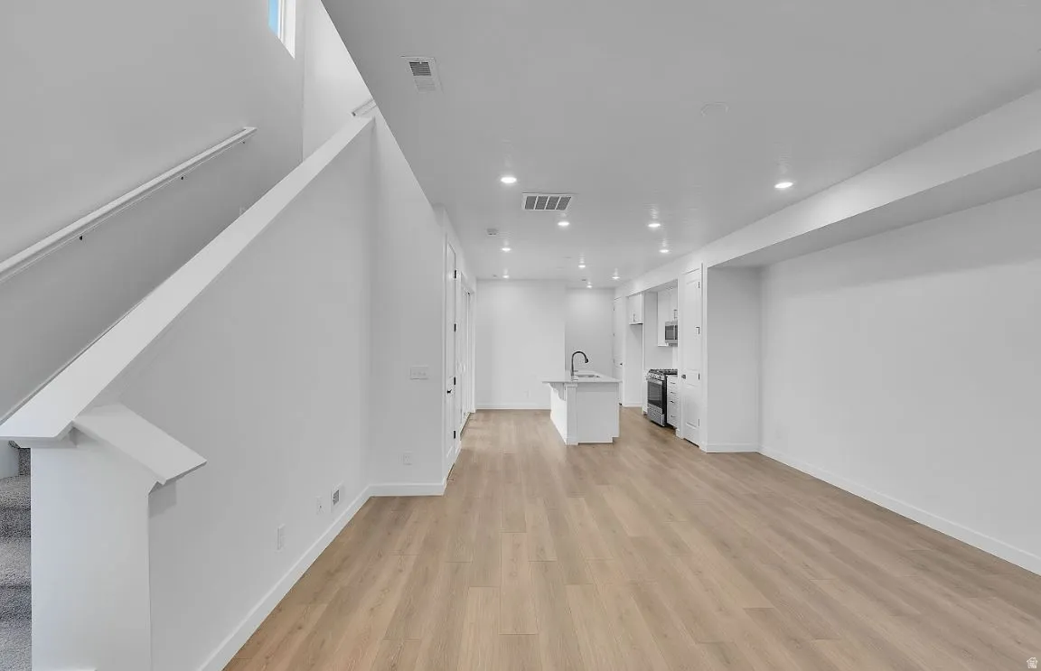 Unfurnished living room featuring recessed lighting, stairs, and light wood finished floors