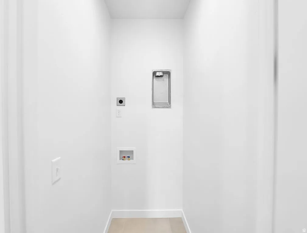 Laundry area with electric dryer hookup, washer hookup, and light tile patterned floors