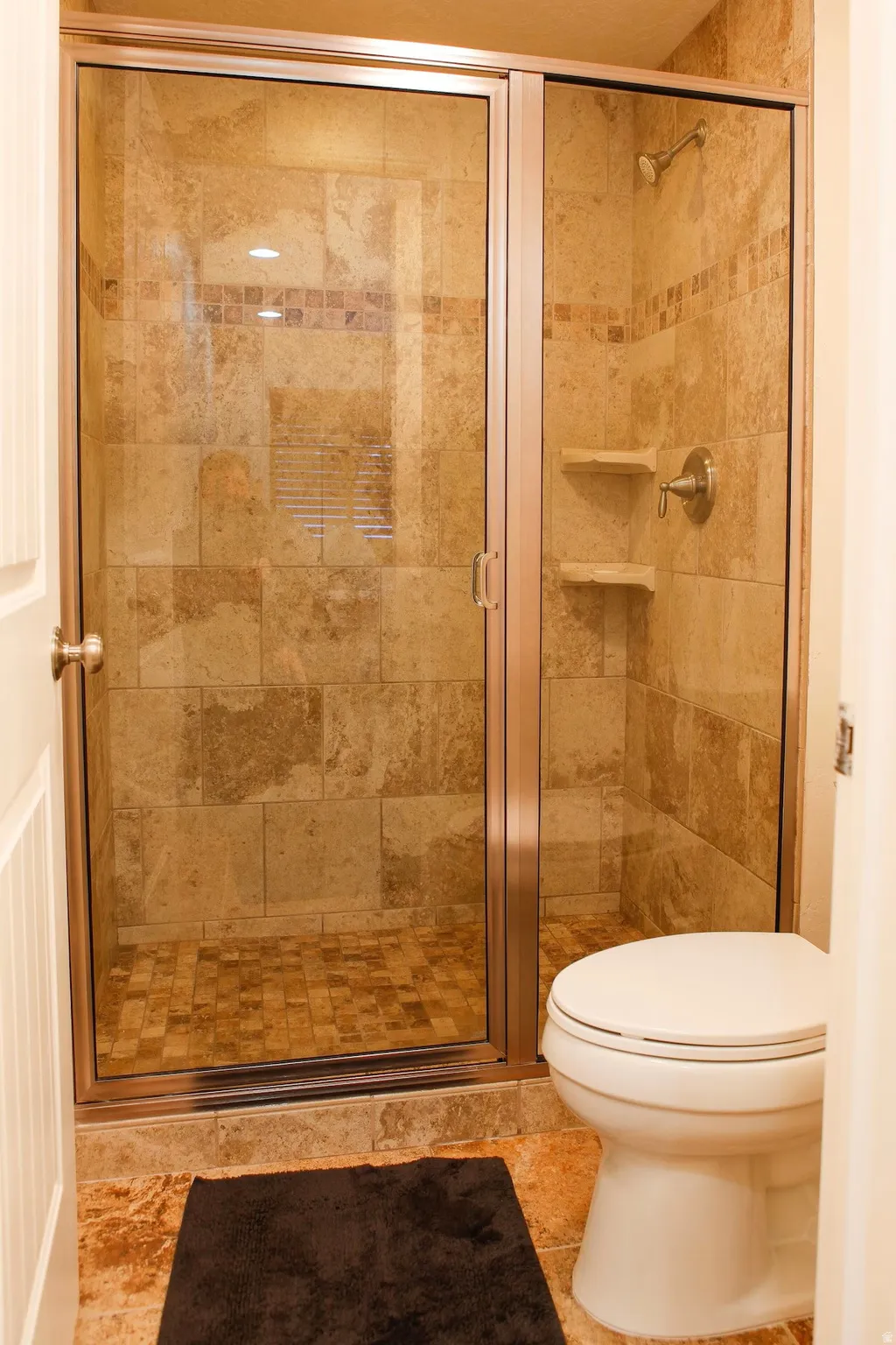 Full bathroom featuring a stall shower and toilet