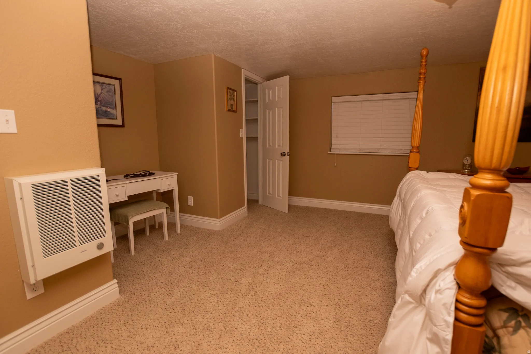 Bedroom featuring a textured ceiling, heating unit, and light colored carpet