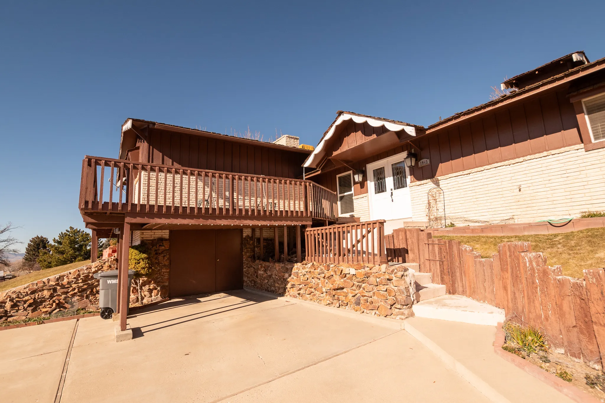 View of front of home with a deck, board and batten siding, stairs, and a patio area