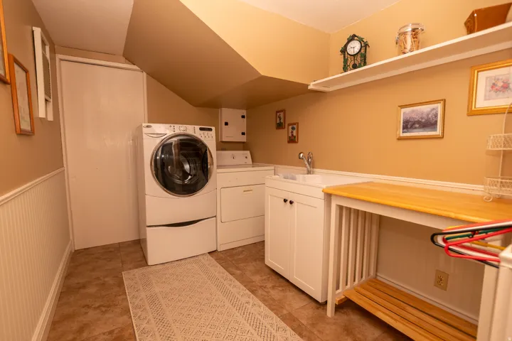 Washroom featuring washer and clothes dryer, cabinet space, lofted ceiling, and a wainscoted wall