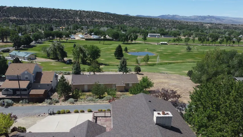 Property with expansive golf course frontage featuring mature trees, a water feature, and distant mountain ranges