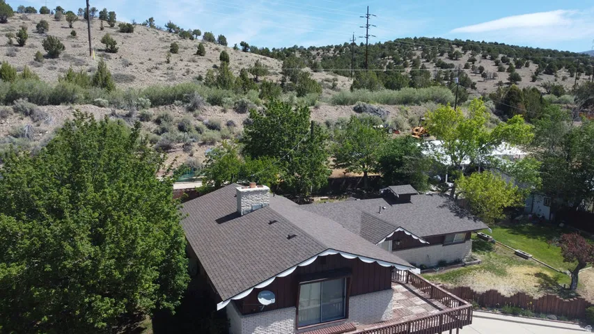 Multi-level residential property with a shingle roof and a stone chimney