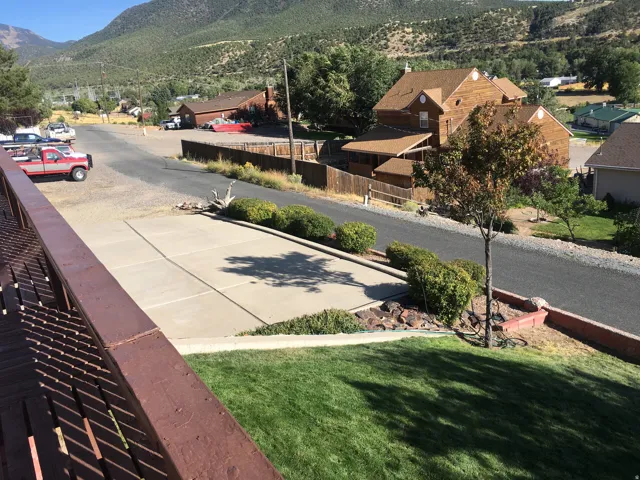 View of asphalt street featuring a mountain view, a residential view, curbs, and sidewalks