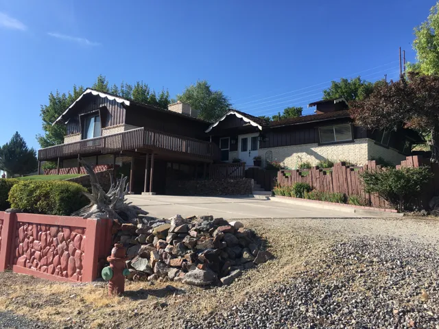 View of front of property with board and batten siding, a wooden deck, and brick siding