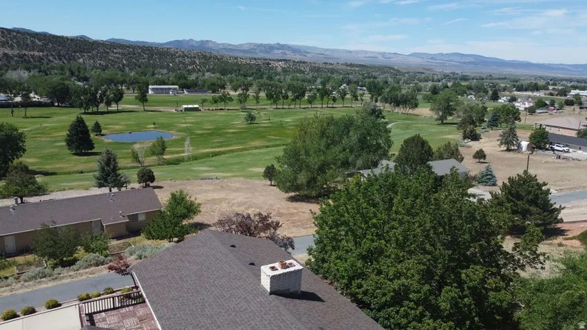 Expansive golf course setting featuring green fairways, scattered trees, and a visible pond