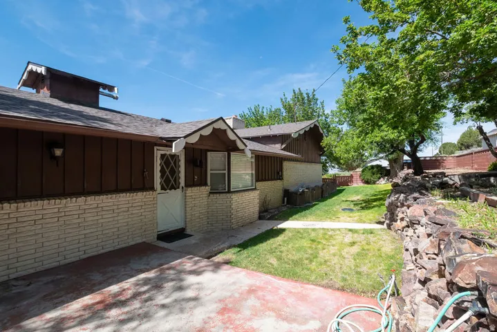 Exterior featuring light-colored brick siding, dark wood-paneling, and a pitched shingle roof