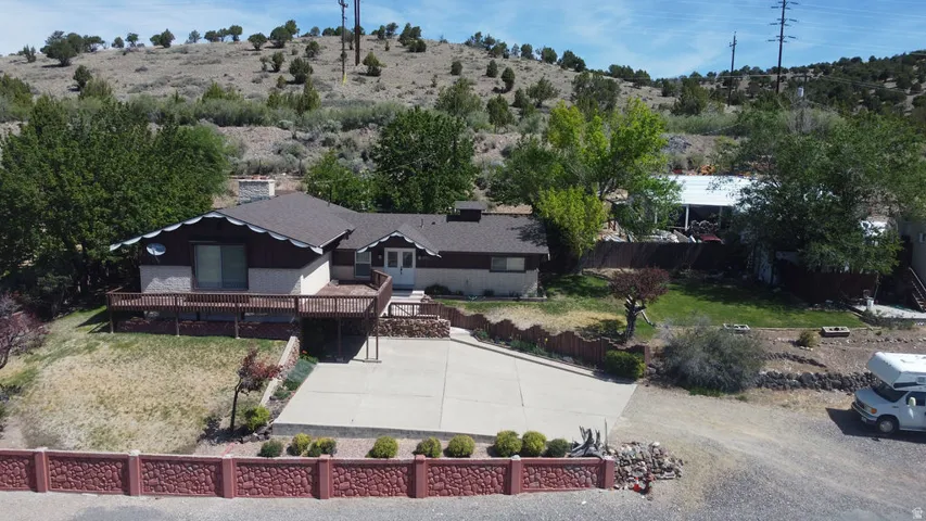 Single-story residence featuring a wood deck, concrete driveway, and a decorative stone-finish fence