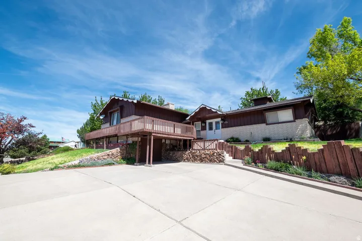 Multi-level architectural style featuring a prominent upper-level deck with a railing, a stone-accented facade, and dark-stained exterior siding