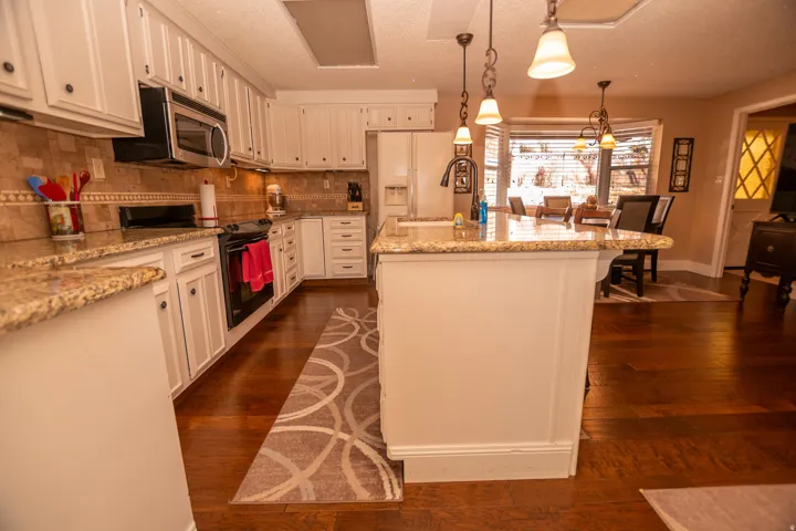 Kitchen featuring electric range, decorative light fixtures, a textured ceiling, light stone countertops, and backsplash