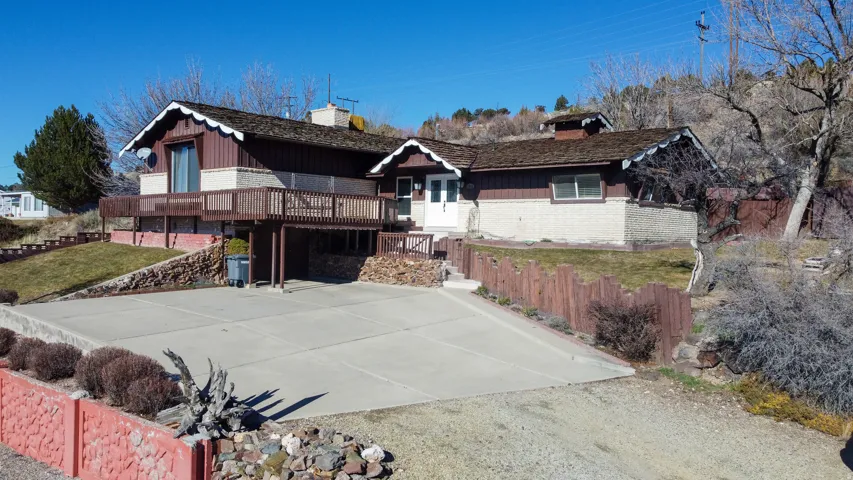 View of front of property with a deck, brick siding, and a chimney