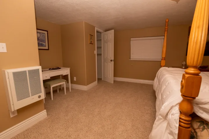 Bedroom featuring a textured ceiling, heating unit, and light colored carpet