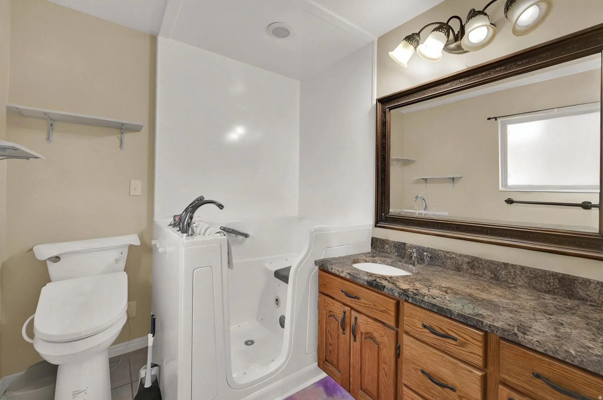Primary bathroom featuring a jetted walk-in tub and vanity