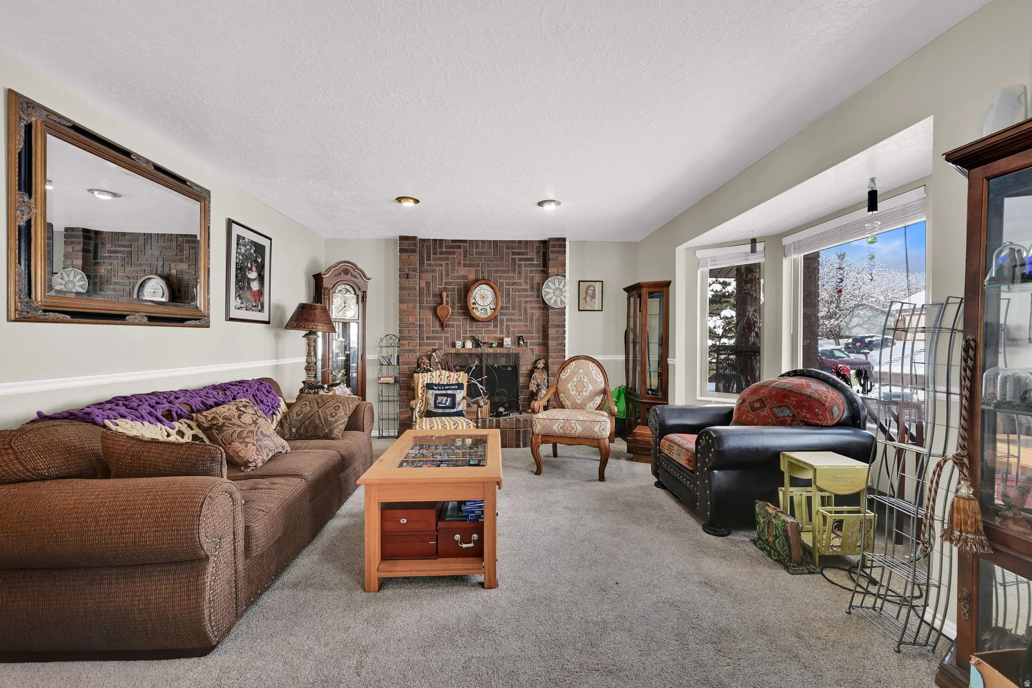 Living room featuring carpet floors, a brick fireplace, and a textured ceiling