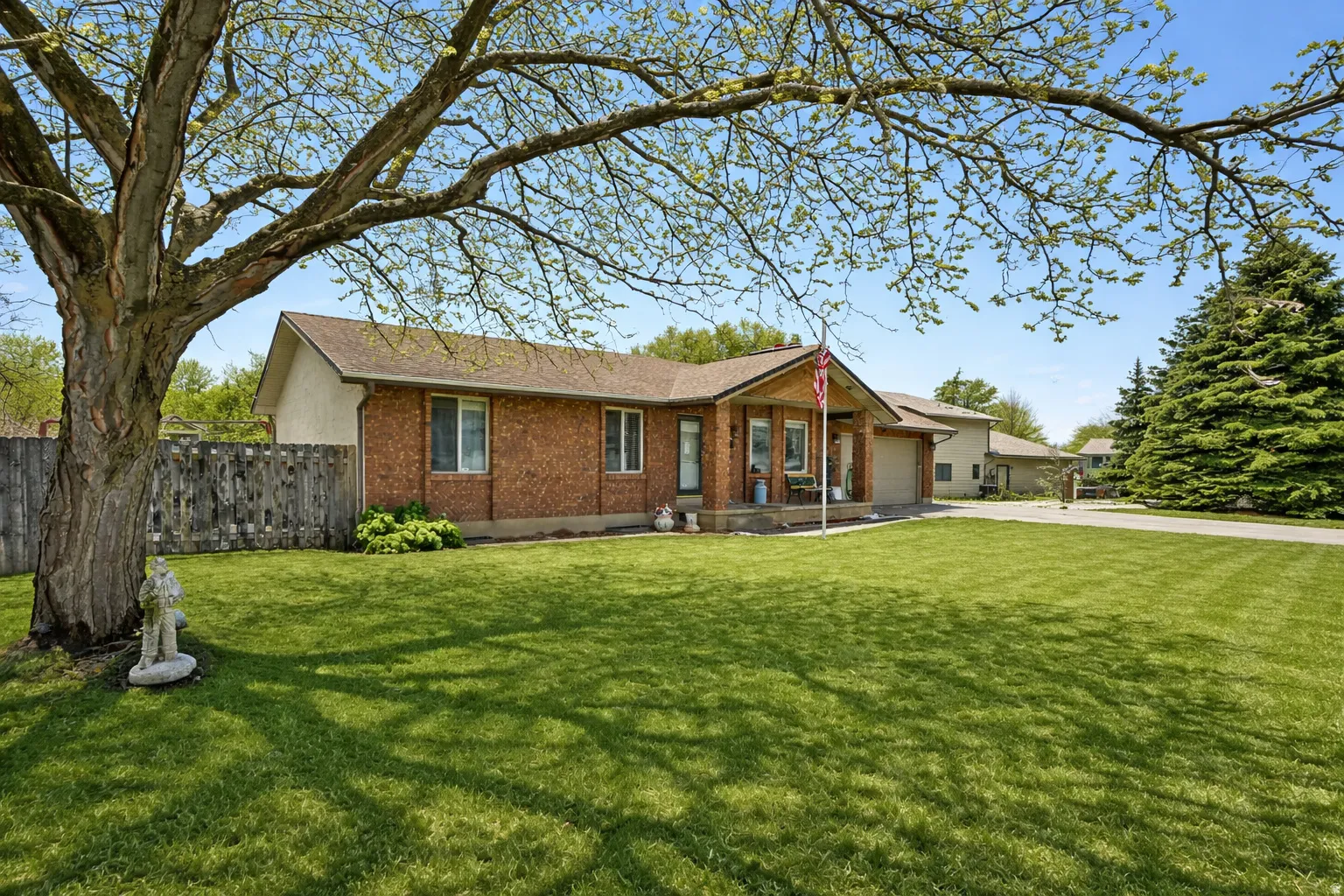 Single story home with brick siding, a garage, and driveway