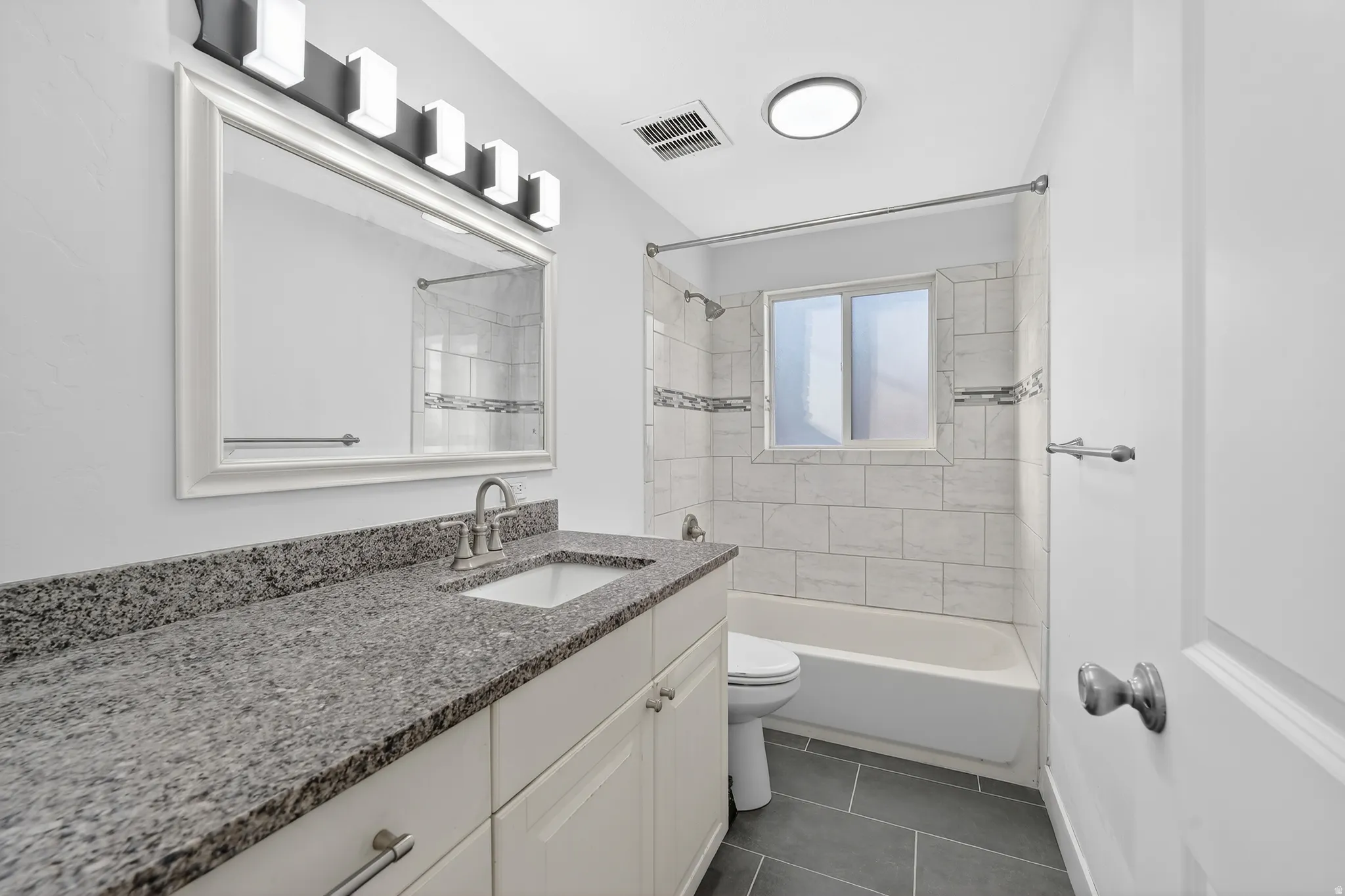 Full bath with vanity, bathtub / shower combination, and dark tile patterned floors