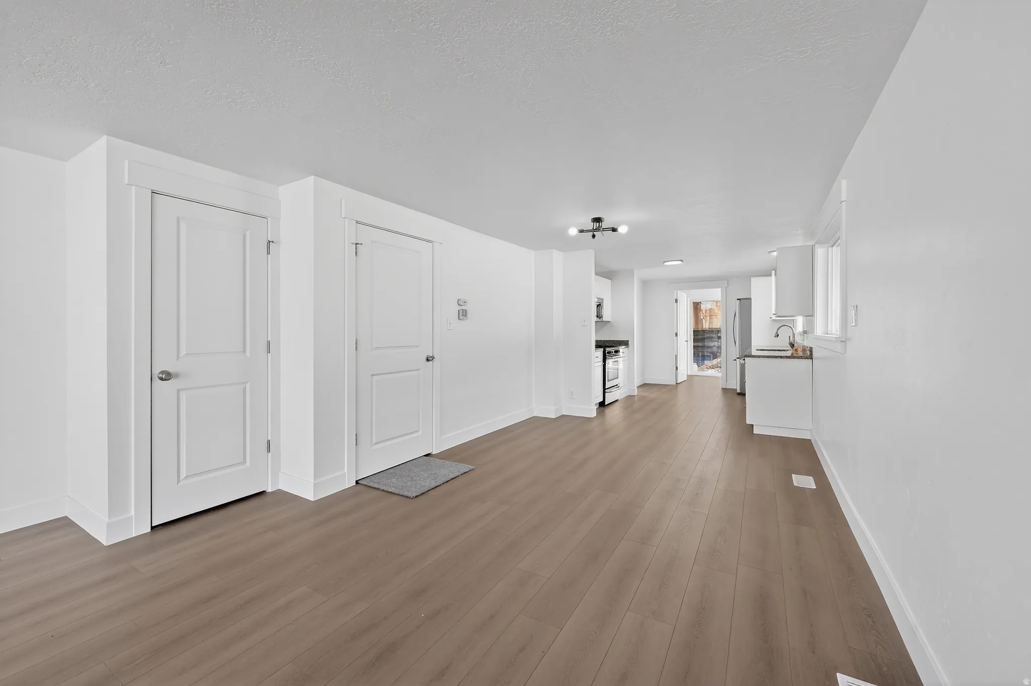 Unfurnished living room featuring light wood-type flooring and a textured ceiling